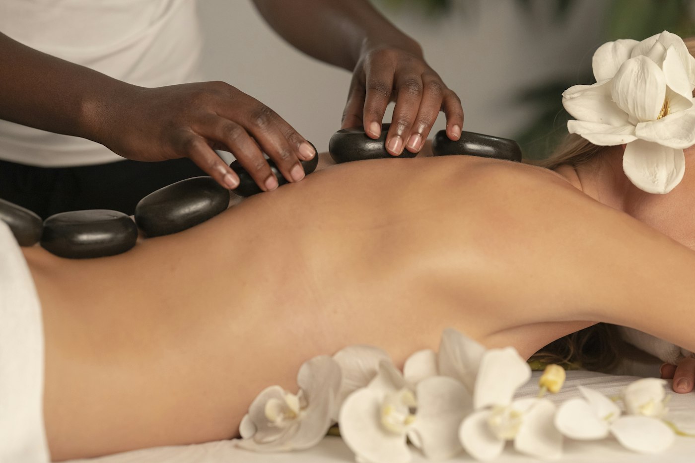 Massagem com pedras quentes e flores sobre as costas